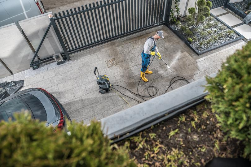 A pressure washing professional cleaning a driveway