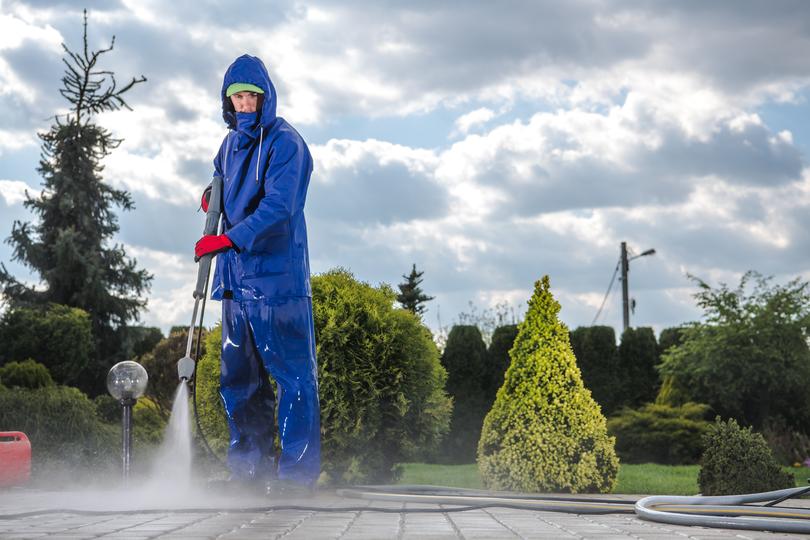 A pressure washing professional cleaning a driveway