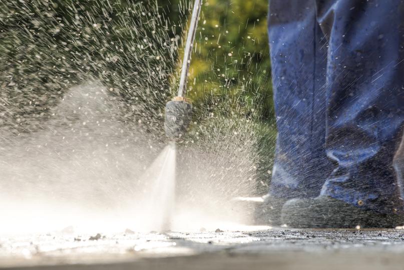 A pressure washing professional cleaning a driveway