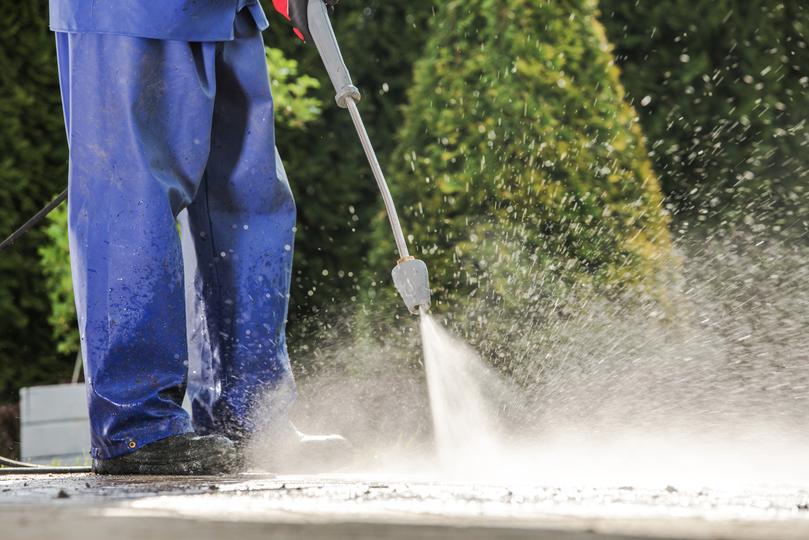 A pressure washing professional cleaning a driveway