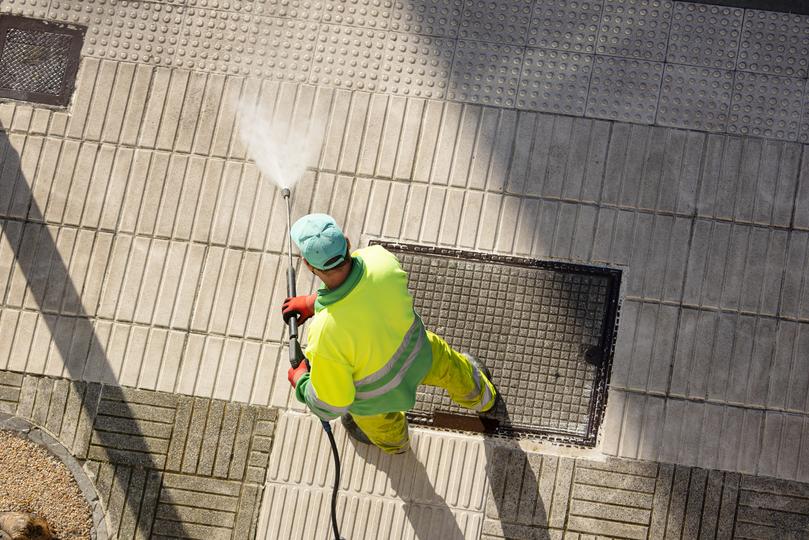 A pressure washing professional cleaning a driveway